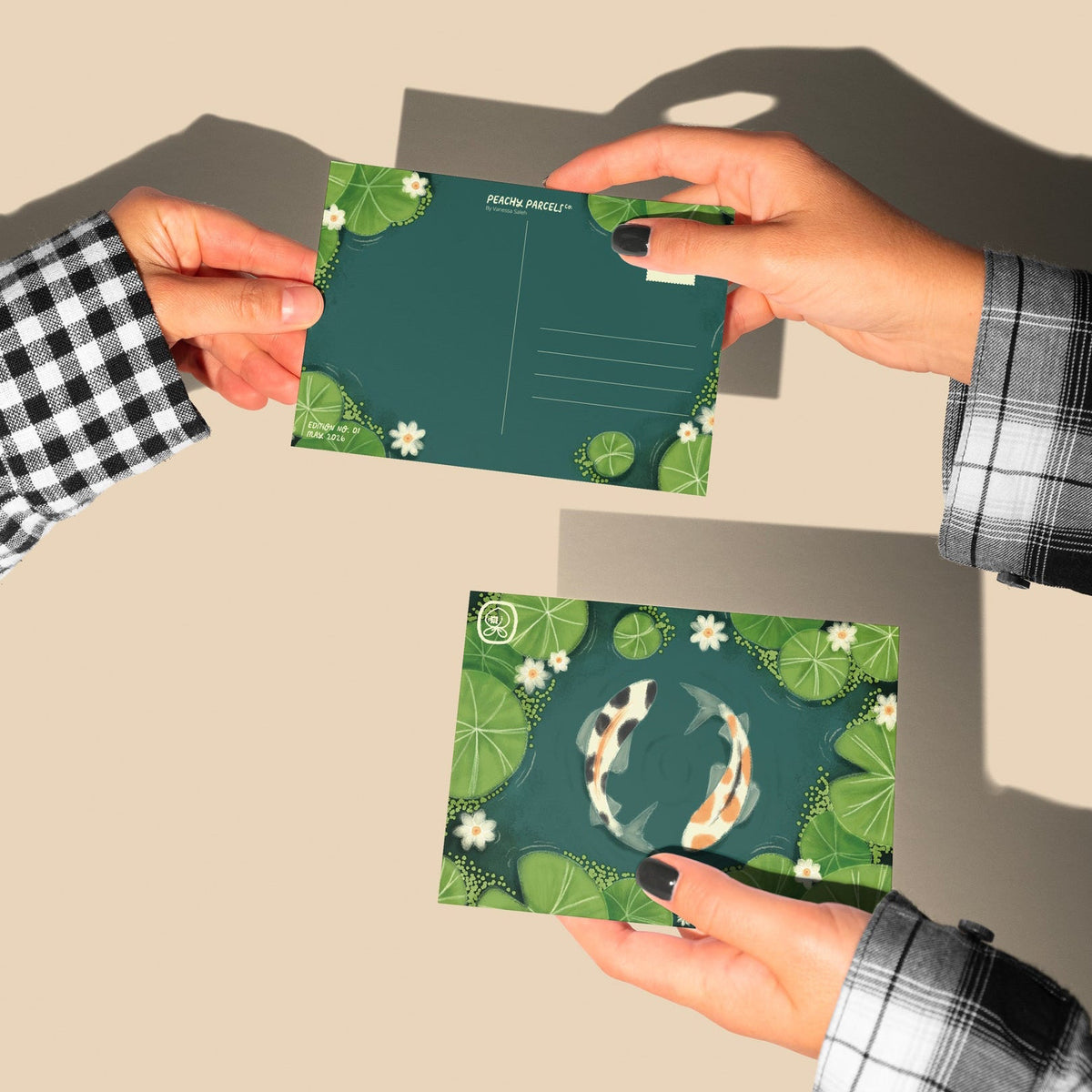 Two people holding green postcards with floral designs on a beige surface.